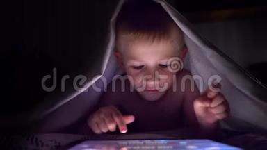 年轻的金发男孩在平板电脑上玩电脑游戏。